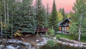 A cabin with a deck, surrounded by trees and a pond. - New Listing! Arrowhead Luxury Home | Private Pond | Fire Pit + Pool Table (Edwards)