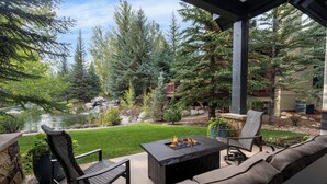 A patio with outdoor seating, a fire pit, and a view of a pond and trees. - New Listing! Arrowhead Luxury Home | Private Pond | Fire Pit + Pool Table (Edwards)