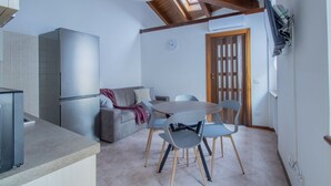 A compact kitchen with a refrigerator, a dining area with a table and chairs, a sofa, and a wooden door. - GuestHost - Cozy and practical 62 square meters apartment, perfect for four people, located on the second floor of a renovated period building (NO elevator).The property is located in the center of Negrar di Valpolicella, a hilltop town in the province o (Negrar di Valpolicella)