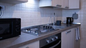 A modern kitchen with a gas stove, microwave, sink, and a kettle. - GuestHost - Cozy and practical 62 square meters apartment, perfect for four people, located on the second floor of a renovated period building (NO elevator).The property is located in the center of Negrar di Valpolicella, a hilltop town in the province o (Negrar di Valpolicella)