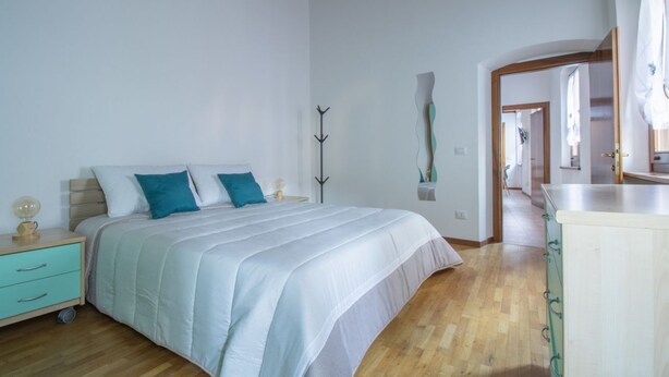 A bedroom with a bed, a nightstand, a dresser, and a mirror.