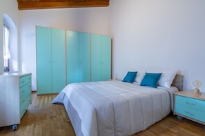 A bedroom with a bed, a wardrobe, a nightstand, and a dresser. - GuestHost - Cozy and practical 62 square meters apartment, perfect for four people, located on the second floor of a renovated period building (NO elevator).The property is located in the center of Negrar di Valpolicella, a hilltop town in the province o (Negrar di Valpolicella)