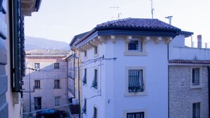 A narrow street with buildings, a parked car, and a mountain in the background.