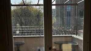 Ovi, josta avautuu näkymä ulkoilma-alueelle, jossa on tiililattia, metallikaide ja penkki.