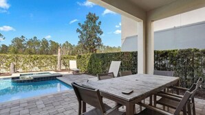 Un patio cubierto con piscina, mobiliario exterior y vistas del paisaje circundante.