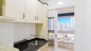 A kitchen with white cabinets, a black countertop, and a window with a city view. - 3-bedroom Apt Only 300m From the Beach Ejs0803 (Balneário Camboriú)
