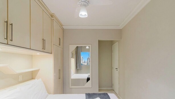 A hotel room with a bed, a wardrobe, a mirror, and a view of the city through a window. - 3-bedroom Apt Only 300m From the Beach Ejs0803 (Balneário Camboriú)