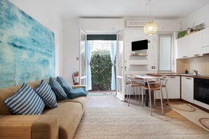 Un soggiorno moderno con un divano, cuscini a righe, un grande quadro astratto e vista su un balcone attraverso una porta vetrata.