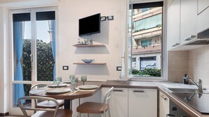 Une cuisine moderne avec un coin repas, un téléviseur fixé au-dessus du comptoir et une vue sur le balcon extérieur.