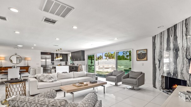 A modern living room with a white sofa, patterned armchairs, and a fireplace. - Luxury 3 bed 2 bath pool spa home with 29 day minimum (Palm Desert)