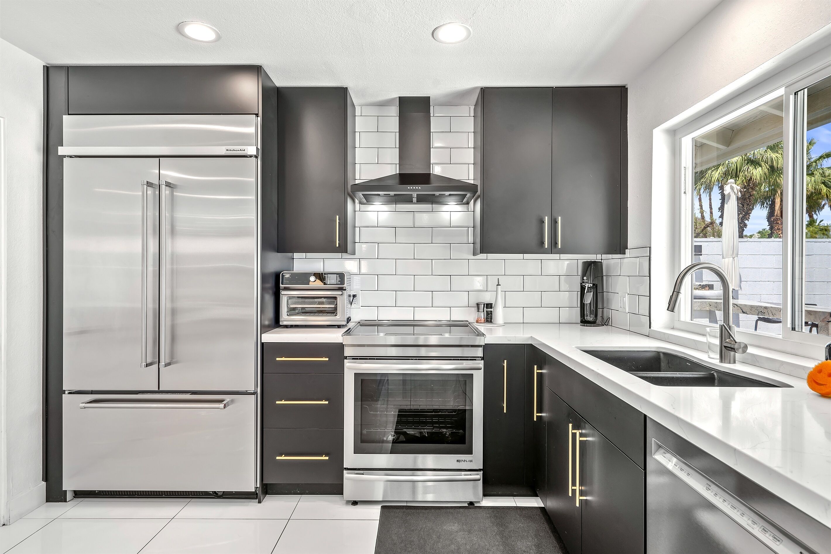 Una cocina moderna con refrigerador de acero inoxidable, horno y microondas empotrados.