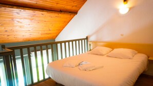 A bedroom with a wooden ceiling, a white bed with pillows, and a nightstand. - Ushuaïa Villages-Domaine de Scott Duplex Spruce 25 (Montigny-en-Morvan)