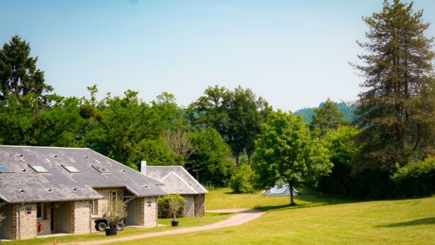 A stone building with a sloped roof and a paved driveway leading to a grassy area. - Ushuaïa Villages-Domaine de Scott Duplex Spruce 25 (Montigny-en-Morvan)