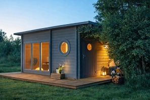 A modern cabin with large windows, a deck, and a circular door. - Tiny House Cabin aan Elfstedenwater bij Leeuwarden (Weidum)