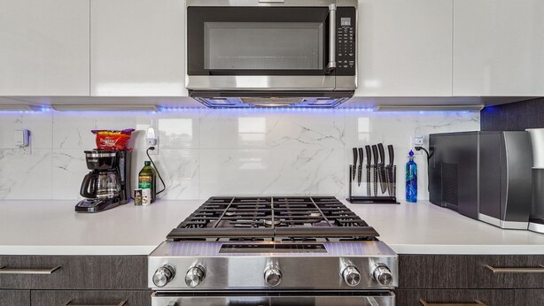 Una cocina moderna con microondas integrado, estufa a gas y electrodomésticos de acero inoxidable.