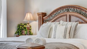 A neatly made bed with a wooden headboard, a bedside lamp, and a potted plant.