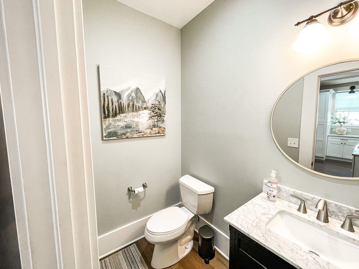 A bathroom with a toilet, sink, and mirror.