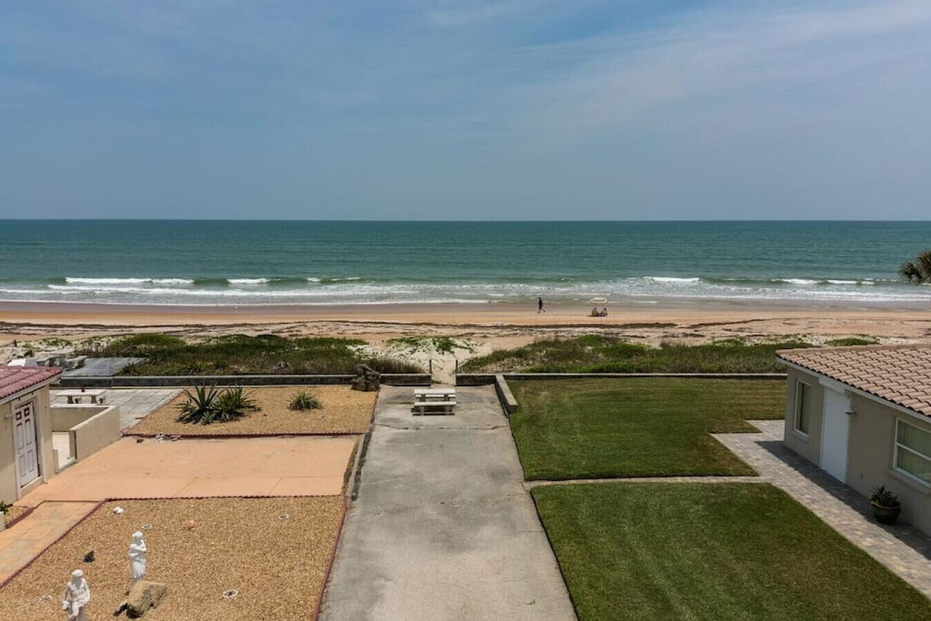 Ein Wohngebiet mit Blick auf den Strand, einer gepflasterten Auffahrt und einem Rasen.