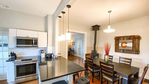 A modern kitchen with a central island, dining area with chairs, and a large wooden table. - 2622 N Nevada (Colorado Springs)