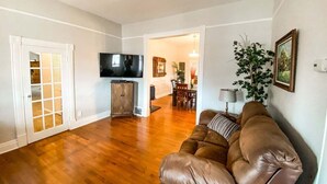 A living room with a brown leather sofa, a television, and a dining area with a table and chairs. - 2622 N Nevada (Colorado Springs)
