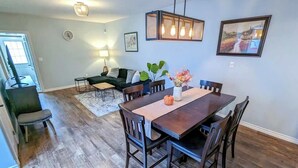 Un coin repas avec une table et des chaises en bois, un vase rempli de fleurs et un tableau accroché au mur.