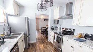 Une cuisine moderne avec des meubles blancs, un réfrigérateur en acier inoxydable, un four à micro-ondes et un four traditionnel.