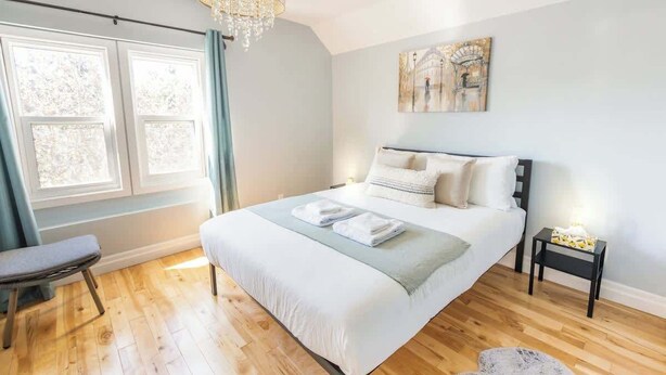Une chambre à coucher avec un grand lit, un banc, une table de chevet et un lustre.