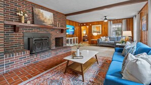Ein Wohnzimmer mit Kamin aus Backstein, einem blauen Sofa und einem Fernseher.