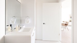 A modern bathroom with a large mirror, two sinks, and a door leading to a dining area. - 2880 U505 Skytop Perspective at Espadin (Denver)