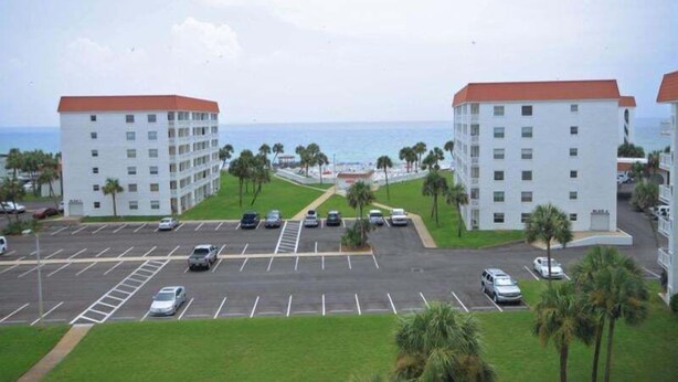Ein Hotel mit Parkplatz, Blick auf den Ozean und Strand im Hintergrund.