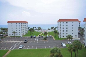 Hotel med parkeringsplads, havudsigt og en strand i baggrunden.