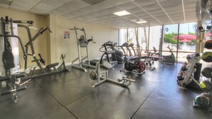 Ein Fitnessstudio mit unterschiedlichen Trainingsgeräten, großen Fenstern und Blick ins Freie.