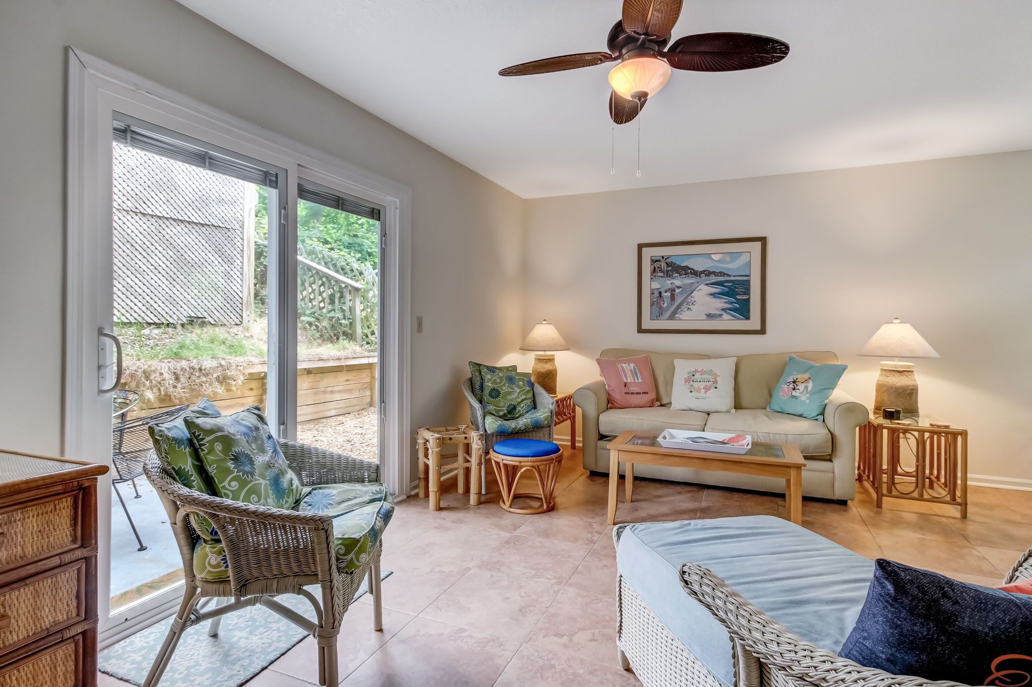 A living room with wicker furniture, a ceiling fan, and a large window.