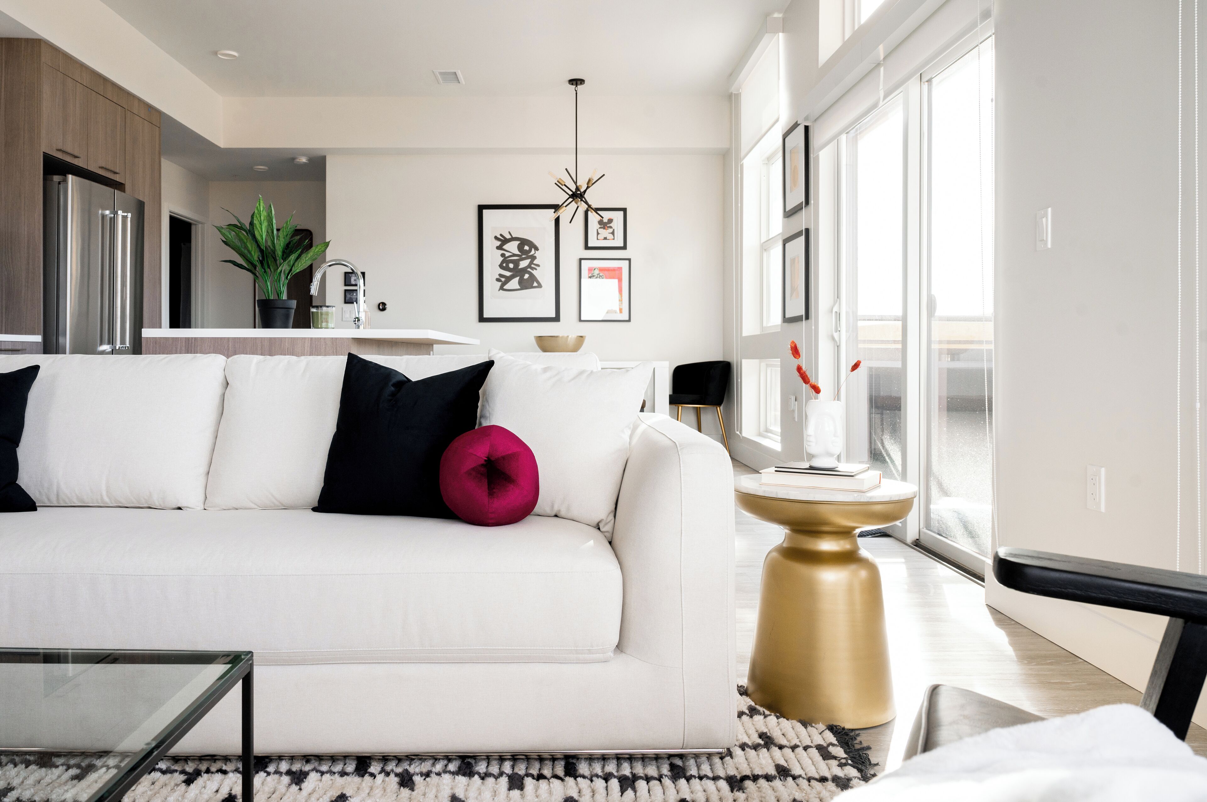 Ein modernes Wohnzimmer mit einem weißen Sofa, einem Glastisch und einem goldfarbenen Beistelltisch.