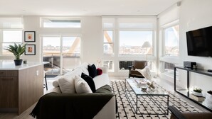 A modern living room with a sofa, coffee table, and a TV. There are large windows and a view of the city. - 2880: Serenity in Style at Espadin (Denver)