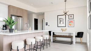 A modern kitchen with a white countertop, stainless steel appliances, and a bar stool seating area. - 2880: Serenity in Style at Espadin (Denver)