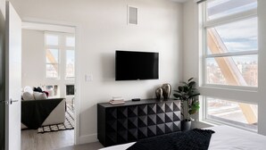 A modern bedroom with a large bed, a TV mounted on the wall, and a city view through a large window. - 2880: Serenity in Style at Espadin (Denver)