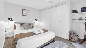 A bedroom with a bed, bedside tables, a wardrobe, a shelf with books, and a framed picture on the wall. - 2 min to AUD | Private Getaway w/ Firepit (Kitchener)