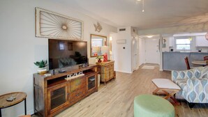 A living room with a wooden entertainment center, a television, a sofa, and a patterned armchair. - 224 El Matador (Fort Walton Beach)