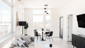 Ein modernes Wohnzimmer mit einer Couch, einem Esstisch, Stühlen und einem Fernseher.