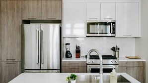 Eine moderne Küche mit einem Edelstahl-Kühlschrank, einer Mikrowelle, einem Herd und einem Spülbecken.