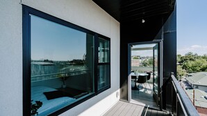 Ein moderner Balkon mit großen Fenstern und Blick auf eine Stadtlandschaft.