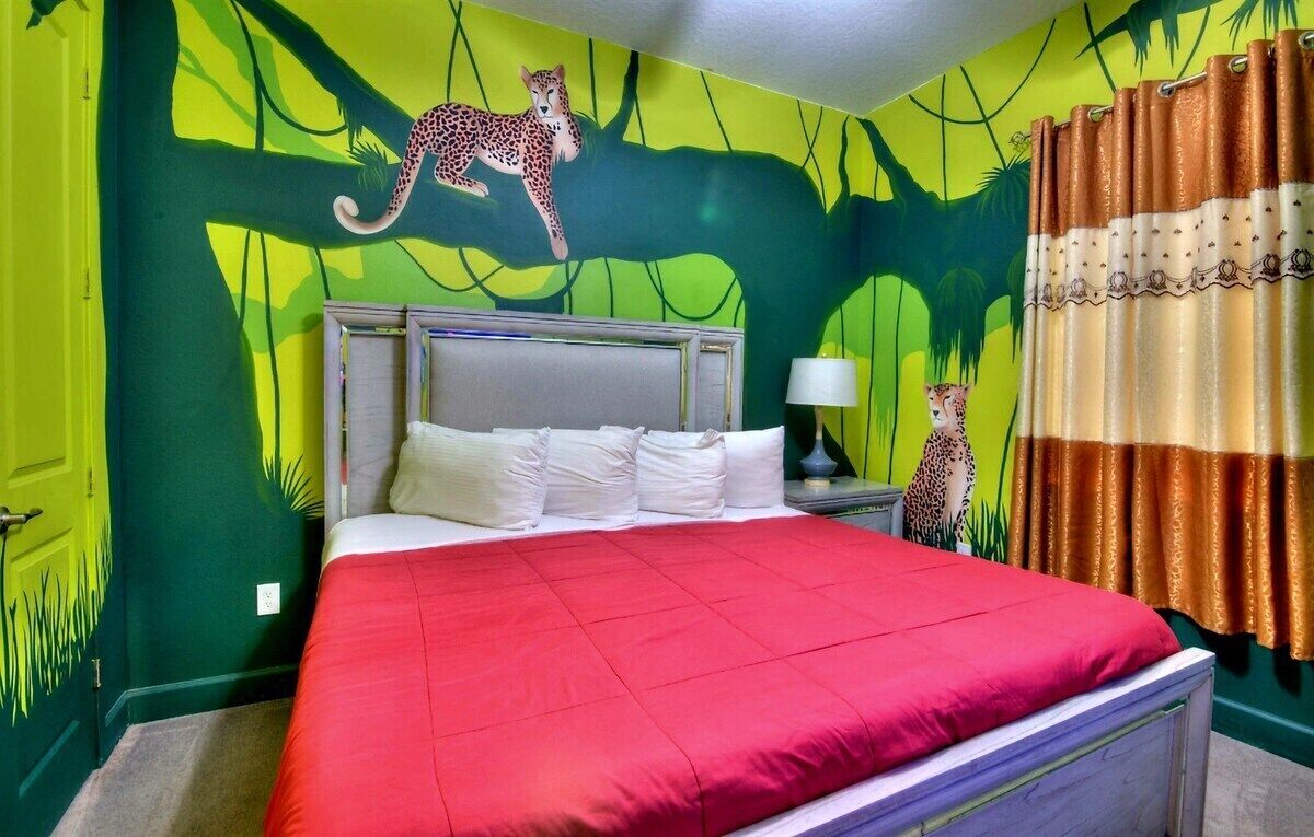 A room with a bed, a nightstand, and a leopard mural on the wall.