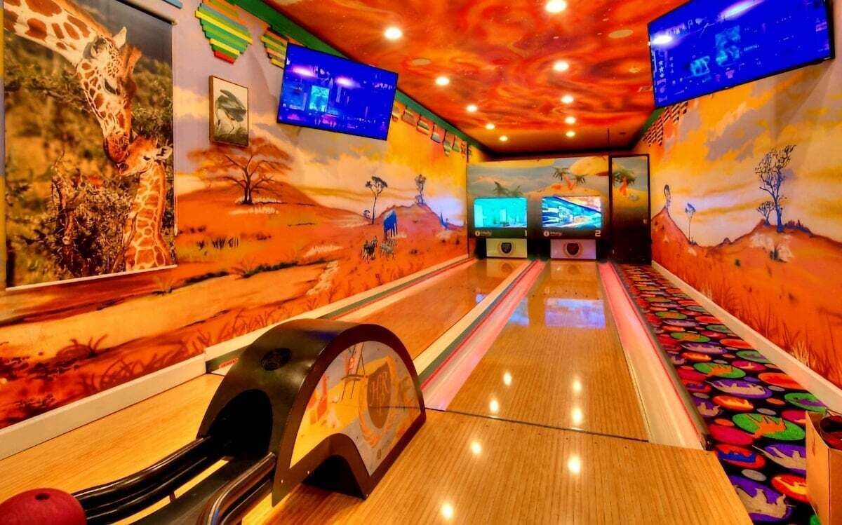 En bowlinghal med farverige vægmalerier og flere skærme, der viser indhold.