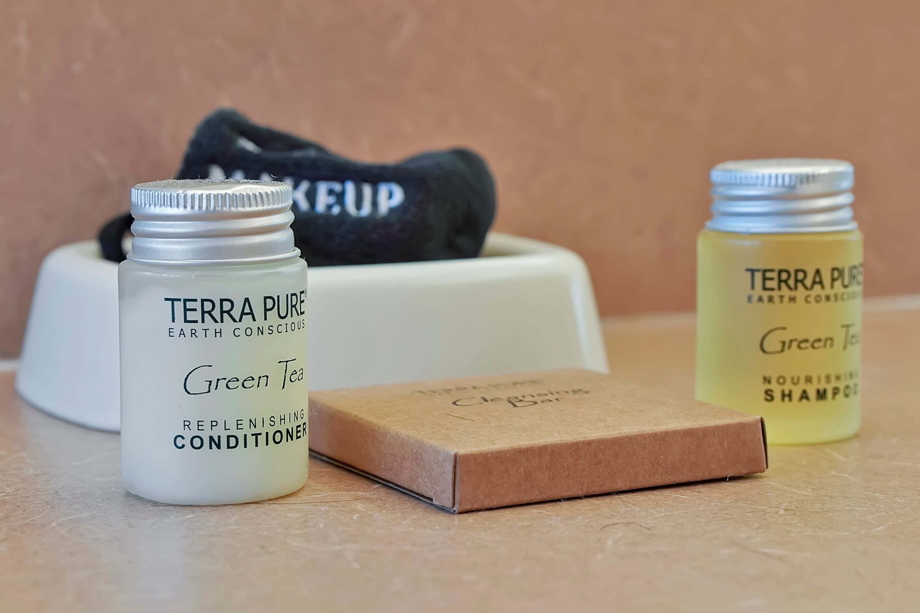 Tre bottiglie di prodotti Terra Pure, un contenitore bianco e una scatola marrone su un piano di lavoro.