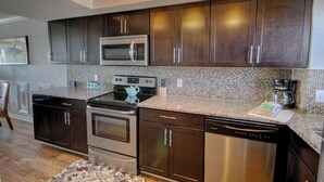 A modern kitchen with dark wood cabinets, stainless steel appliances, and a tiled backsplash. - 243 El Matador (Fort Walton Beach)