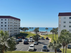A parking lot with several cars, a building with multiple floors, and a view of the ocean. - 243 El Matador (Fort Walton Beach)