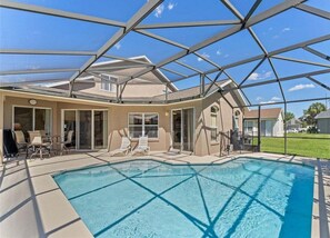 A swimming pool with a glass ceiling, lounge chairs, and a patio area. - 229 Corvina Drive Davenport, 5bed (Davenport)