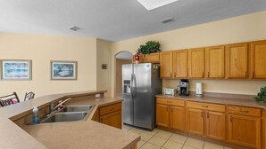 A kitchen with wooden cabinets, a stainless steel refrigerator, a sink, and a countertop. - 229 Corvina Drive Davenport, 5bed (Davenport)