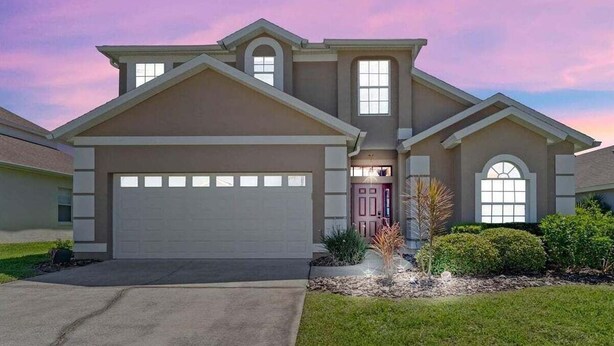 A two-story house with a garage, a front porch, and a well-maintained lawn. - 229 Corvina Drive Davenport, 5bed (Davenport)